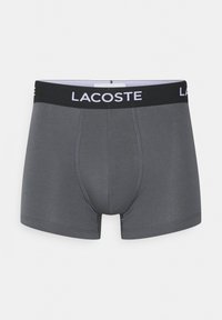 Grijze boxershorts van zachte stof, met een zwarte elastische tailleband waarop het "LACOSTE" logo in het wit is afgebeeld, en een nauwsluitend ontwerp met stikdetails.