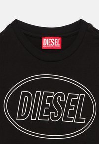 Μαύρο μπλουζάκι με λευκό λογότυπο "DIESEL" μέσα σε οβάλ στο μπροστινό μέρος και κόκκινη ετικέτα στο λαιμό με την επιγραφή "DIESEL For Successful Living."