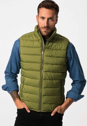 Olivgrüner Puffer-Weste mit vertikalen Nähten, hohem Kragen, Reißverschluss vorne und Seitentaschen. Getragen über einem Jeanshemd mit langen Ärmeln.
