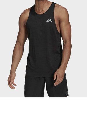 Homme portant un débardeur de sport noir Adidas sans manches et un short noir, debout avec les bras détendus le long du corps.