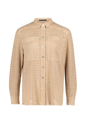 Chemise beige à boutons avec un design perforé, manches longues, deux poches poitrine et boutons argentés. Texture de tissu douce.
