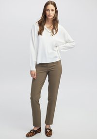 Witte V-hals trui, slim-fit olijfgroene broek en loafers met luipaardprint en zwarte accenten. Zachte stof en ontspannen pasvorm ontwerp.
