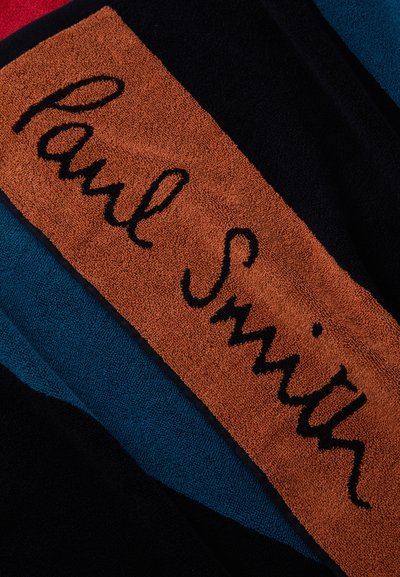 Multicolored towel featuring plush texture. Prominent central orange patch with "Paul Smith" in black stitching. Surrounding colors include navy, teal, and red.