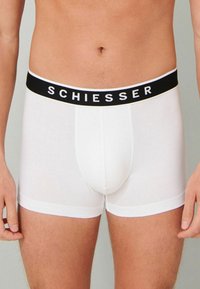 White cotton boxers with a black waistband featuring the brand name "SCHIESSER" in white lettering. Simple and form-fitting design.