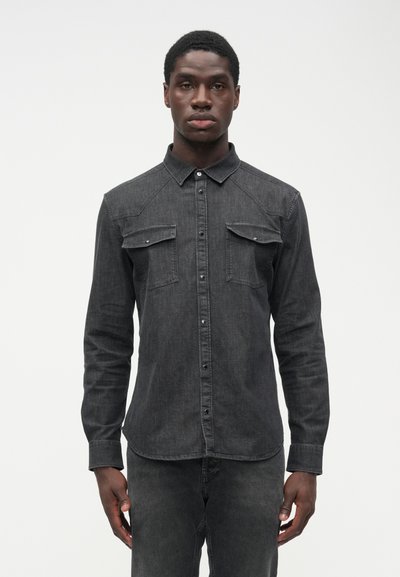 Men's black denim shirt with long sleeves, pointed collar, two chest pockets, button-up front, and subtle texture. Tailored fit.