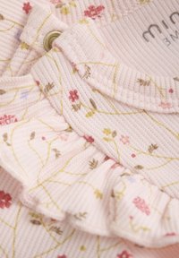 Ribbad rosa tygtopp med blommönster i nyanser av rött, gult och grönt, med volangkrage och tryckknappsförslutning.