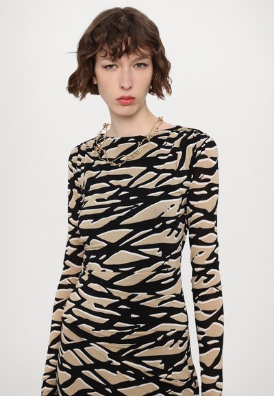Langarm jurk met een zwart, beige en wit abstract patroon, aansluitend ontwerp en een ronde halslijn. Heeft rimpelingen langs het lichaam.