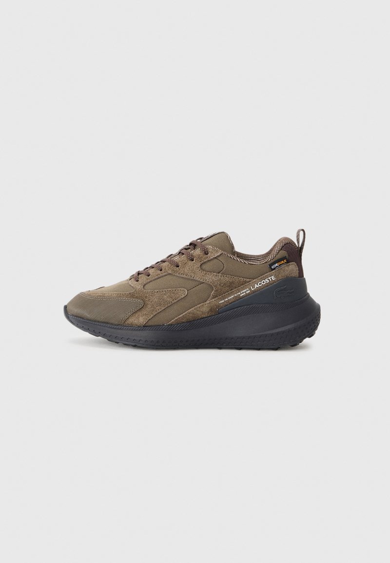 Baskets Lacoste marron et noir avec dessus en textile et suède mélangés, semelle noire, lacets et languette au talon, présentées sur un fond uni.