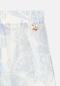 Jasnoniebieska, wzorzysta tkanina z wzorem paisley. Posiada elastyczny pas oraz złoty emblemat w kształcie serca. Miękka w dotyku.