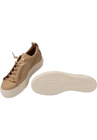 Beżowe skórzane sneakersy z sznurowanym designem, metalowymi oczkami, wyściełanym językiem oraz białą gumową podeszwą z teksturowanym wzorem antypoślizgowym.