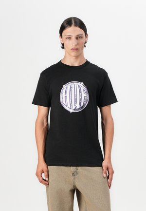 Black cotton t-shirt featuring a circular graphic with the letters "HUF" in white and purple, set against a clean background.