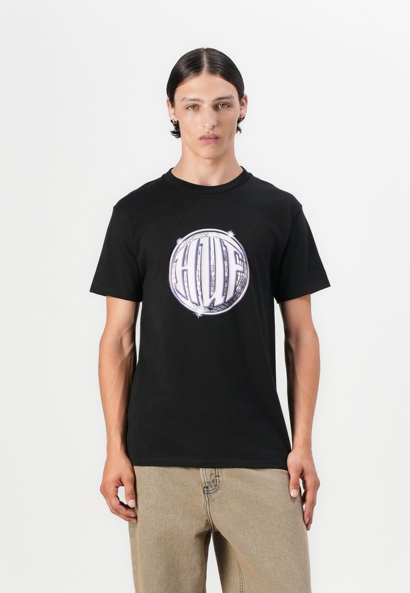 Tricou negru din bumbac cu un grafic circular în care apar literele "HUF" în alb și mov, plasat pe un fundal curat.