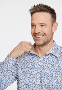 Camicia a bottone floreale con base bianca e motivi blu e gialli, colletto alla francese e tessuto testurizzato.