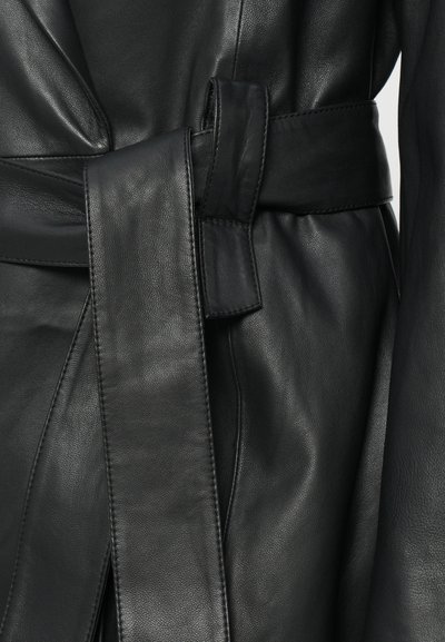 Čierny kožený opasok s hladkou textúrou a širokým dizajnom, ktorý má detail uzla a precízne prešité okraje.