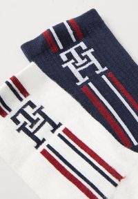 Chaussettes en coton navy et blanc. Présentent des logos tricotés et des rayures horizontales en rouge et bleu. Texture douce, longueur mi-mollet.