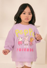 Vijoličasta majica z dolgimi rokavi s potiskom Peppa Pig in prijateljev v rumeni in roza barvi, z rebrastimi manšetami in sproščenim krojem. Pod njo usklajene kratke hlače.