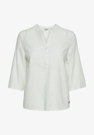 Valkoinen pellavapaita, jossa on pyöreä kaula-aukko ja neljä nappia, kolmanneksen pituiset hihat ja rento malli. Pienen logon löytyy helman kohdalla.