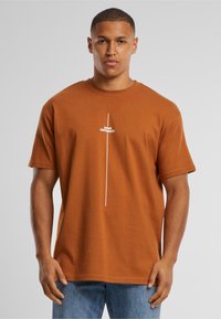 Bruine katoenen T-shirt met korte mouwen, met een witte tekstgrafiek "THINK DIFFERENT" verticaal gecentreerd op de voorkant.