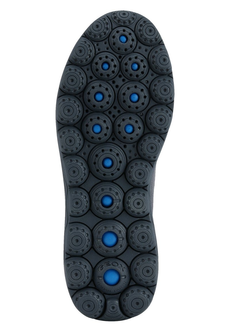 Semelle de chaussure en caoutchouc noir avec motifs circulaires et accents bleus, dotée de cercles texturés surélevés pour une meilleure adhérence et flexibilité.