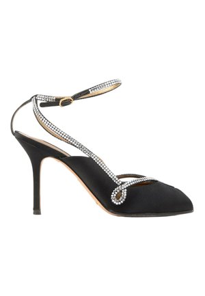 Zapato negro de tacón alto con punta afilada, tira en el tobillo y cadenas decorativas de piedras brillantes que envuelven el pie y el tobillo.