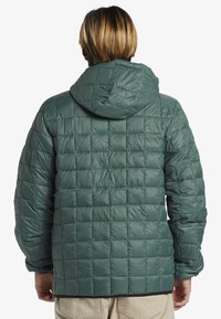 Green puffer jacket with a quilted design, hood, and elastic cuffs. Smooth texture, lightweight material, and a square pattern throughout.