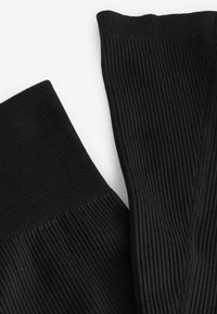 Black ribbed fabric with a textured surface; features a seamless top edge and visible stitching along the side.