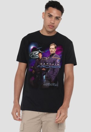 Man wearing black t-shirt featuring two Star Trek Enterprise characters in uniforms and a spaceship against a space background.
