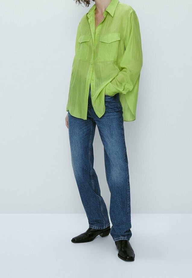 Lime green, sheer button-up shirt with two chest pockets, paired with blue straight-leg jeans and black pointed-toe boots.