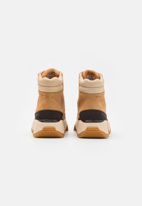 Brune mokkasiner med beige krage og sort mellomsåle. Teksturerte detaljer og gummisåle med spor for bedre grep.