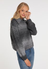 Grijze gebreide trui met een gradient patroon, voorzien van een kraag en lange mouwen, gemaakt van zacht textuur materiaal. Gepaard met denim jeans.