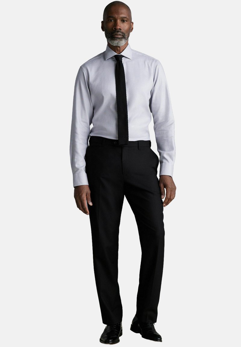 Tenue formelle composée d'une chemise à motifs gris clair, d'une cravate noire et d'un pantalon noir. Textures lisses et coupe ajustée sont évidentes.