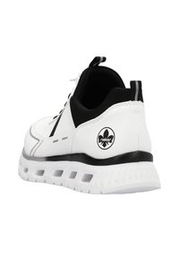 Baskets blanches avec des accents noirs, présentant un matériau lisse, un design arrondi, une semelle texturée et un détail de logo au niveau du talon.