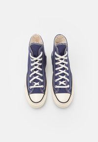Høje sneakers i marineblå lærred med hvide snørebånd, gummitåhætte og kontrastfarvet cremefarvet sål. Har hvide syninger og logo på siden.