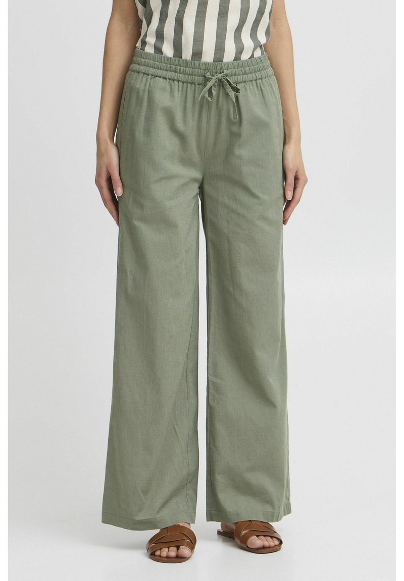Pantaloni ampi verde chiaro realizzati in un tessuto morbido, con una vita elastica dotata di coulisse e tasche laterali.