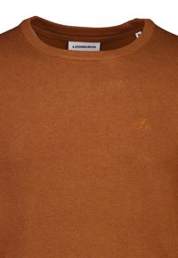 Bruine gebreide trui met een ronde hals en geribde manchetten. Heeft een klein geborduurd logo aan de voorkant, gemaakt van een zachte, textuurrijke stof.