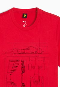 Lysrød T-shirt prydet med sorte tekniske tegninger af en Formel 1-bil, der viser side- og topvisninger, med Puma- og Ferrari-logoer.