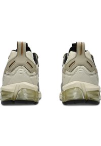 Baskets présentant un design beige et noir, tige synthétique texturée, talon rembourré et semelle en caoutchouc transparent pour un amorti supplémentaire.