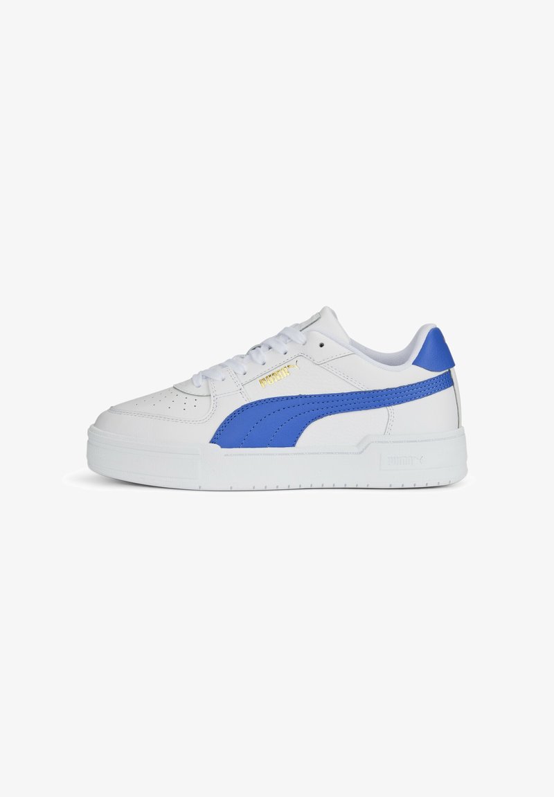 Baskets basses blanches Puma avec une bande bleue sur le côté, languette de talon bleue, bout perforé, lacets blancs et logo Puma doré près des lacets.