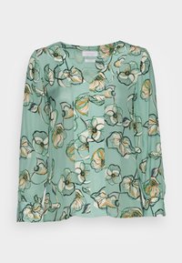Blouse florale en bleu sarcelle clair, avec des manches longues, un décolleté en V et des motifs de fleurs colorées avec des contours noirs. Fabriquée dans un tissu lisse et léger.