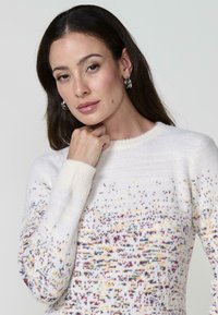 Pulover tricotat de culoare albă, cu un model colorat format din puncte mici în nuanțe de galben, roșu și albastru. Dispune de guler tip crew neck și manșete rib la baza mânecilor. Textură moale.
