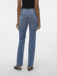 Jeans de ganga azul com um corte reto, apresentando uma cintura média, bolsos traseiros e detalhes de costura subtis. Usados com calçado preto.