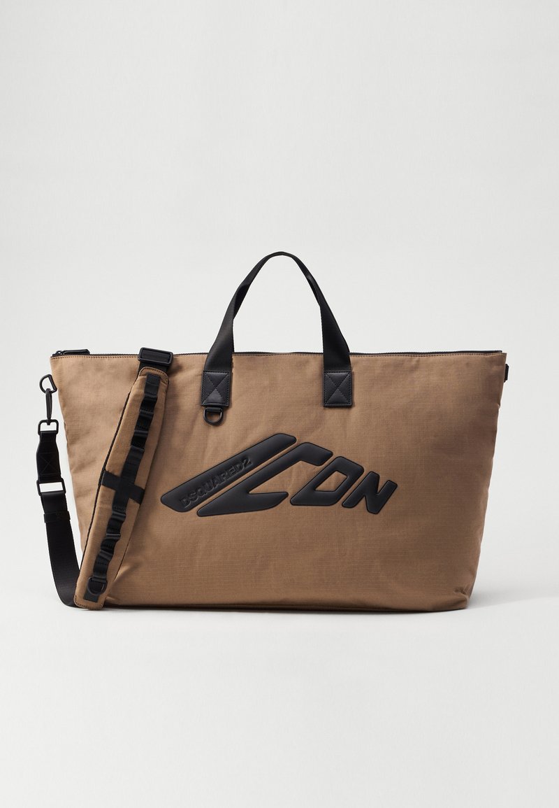 Brun nylon tote bag med sorte detaljer, udstyret med dobbelte håndtag, en aftagelig rem og et forreste logo i forhøjet sort materiale.