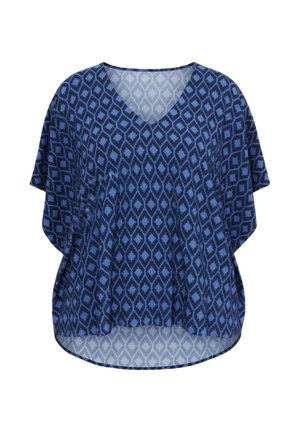 Blouse bleue à col en V, coupe ample avec un motif géométrique en losanges dans différentes nuances de bleu sur fond blanc.