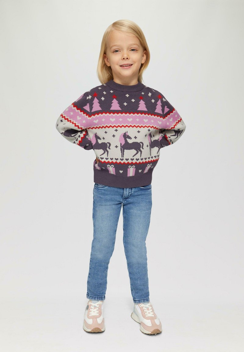Pull en laine violet foncé avec des motifs d'arbre rose et de licorne. Associé à un jean bleu et des baskets pastel, offrant un look confort et ludique.