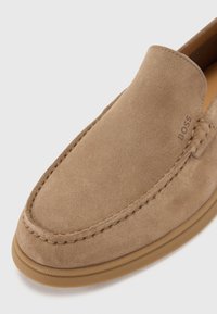 Šviesiai ruda Suede stiliaus avalynė be raištelių, su suapvalintu pirštu, kontrastingomis siūlėmis ir tekstūruota guma. Ant šono išraižytas "BOSS" logotipas.