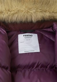 Purple insulated jacket interior featuring a faux fur collar and a care label with brand name "reima" and size information.