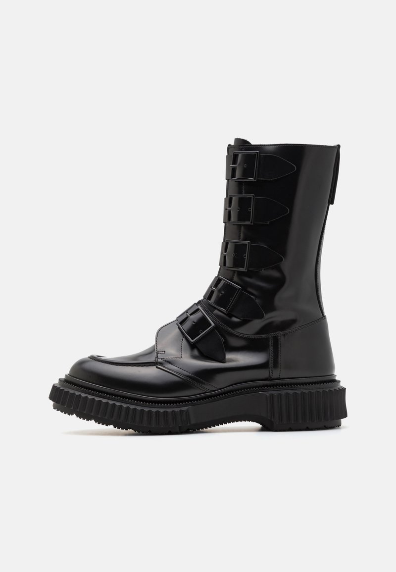 Black leather knee-high boots with four adjustable buckles and a thick, ribbed outsole. Smooth texture, rounded toe, and a polished finish.