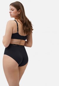 Sostén negro y braguitas de cintura alta con detalle de encaje. Textura suave y diseño simple. Tirantes ajustables y cierre de gancho en la parte posterior.