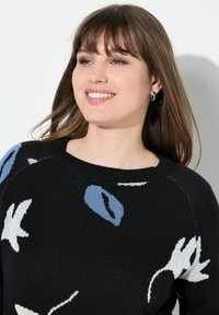 Schwarzer Strickpullover mit blauen und weißen Blumenmustern. Verfügt über einen Rundhalsausschnitt und eine lockere Passform. Glatte Textur und gerippte Bündchen.