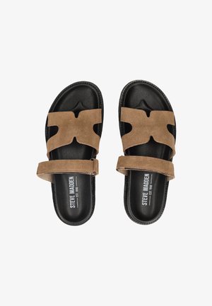 Sandali neri con suola scivolosa, cinturini incrociati in suede marrone e cinturini regolabili alla caviglia, marchiati con "Steve Madden" sulla soletta.